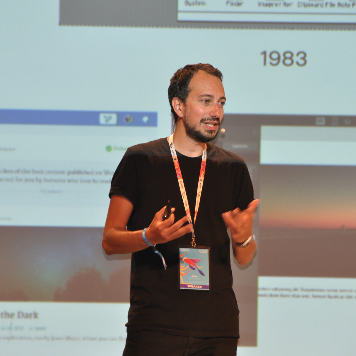Alex Kovalenko speaking on stage at a conference, mid-presentation